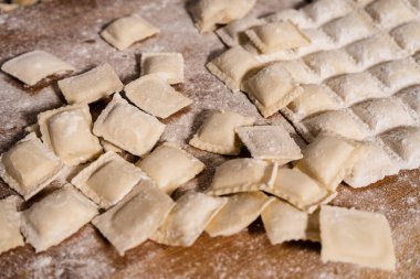 Pişmemiş ravioli ahşap kesme tahtasına un serpiştirilmiş, pişirilmeye hazır.