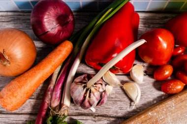 Canlı sebzeler, aromatik otlar ve ahşap bir masada pişirmeye hazır keskin baharatlar.