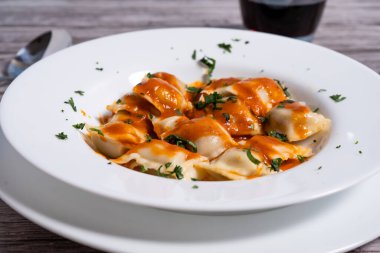 Canlı domates sosu ve taze maydanozla süslenmiş buharlı ravioli İtalyan mutfak geleneğinin özünü somutlaştırıyor.