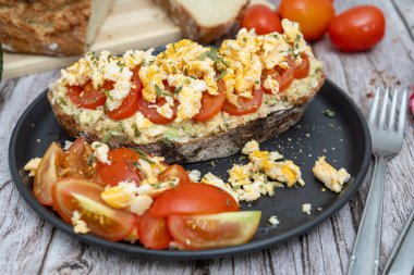 Üstünde guacamole, domates ve çırpılmış yumurta olan Rustik ekmek.