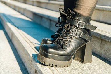 Metal zincirli ve tokalı moda platform botlarının yakın çekimi, basamaklarda kentsel moda sergileniyor