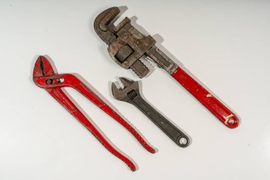 İyi ayarlanmış İngiliz anahtarı, boru anahtarı ve beyaz arka planda aşınma ve yırtık izleri gösteren eklem pensesi.