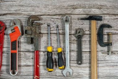 Ahşap bir masa arkasında duran farklı iş araçları işçiliği, bakımı ve tamiratı temsil ediyor.