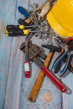 Ahşap yüzeyde, sarı miğferli çeşitli inşaat aletleri var, inşaata hazır.