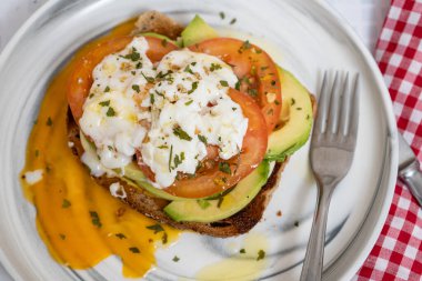 Kavrulmuş yumurtayla dilimlenmiş avokado ve domates.