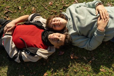 Genç çift güneşli bir sonbahar gününde parkta çimlerde dinleniyor.