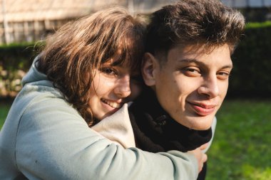 Parkta kucaklaşan genç çift, sevgi ve şefkat dolu bir anın tadını çıkarıyorlar.