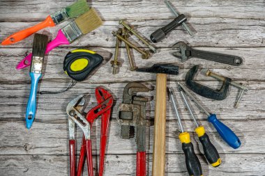 Yıpranmış ahşap yüzeyde düzenlenmiş çeşitli iş araçları, işçiliği ve ev gelişimini temsil eden durgun bir hayat yaratıyor.