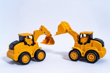 İki sarı oyuncak kazıcısı beyaz bir arka planda karşı karşıya, neşeli ve çekici bir sahne yaratıyorlar.