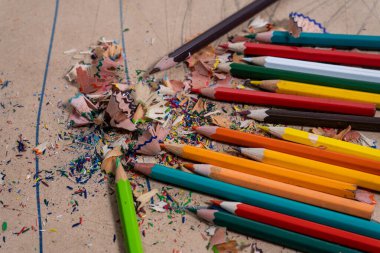 Renkli kalem talaşları karton bir yüzeye saçılmış renkli kalemler.