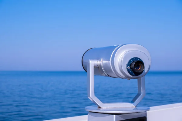 Tourist binoculars. Binocular telescope on the observation deck for tourism. Sea background. Binoculars watching at horizon at ship deck. Travel tourist destination attraction. Copy space for text