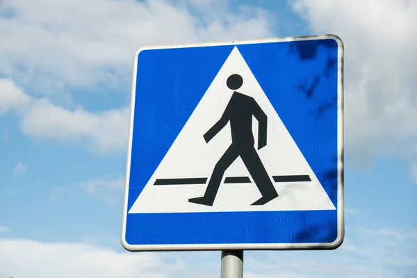 Vertical signage of crosswalk over cloudy sky, road sign pedestrian crossing. Attention road sign. Outdoors
