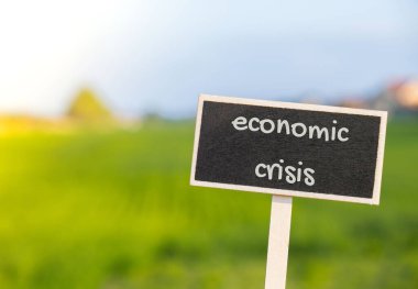 Odaklanmamış tarımsal alan mesajına karşı ECONOMIC CRISIS yazısıyla ahşap bilgi etiketi imzası. Küresel açlık, enflasyon, yüksek fiyatlar, buğday krizi artan yaşam giderleri ve yoksulluk