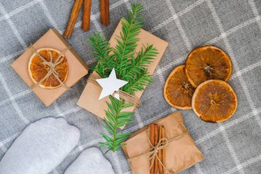Preparation for christmas holidays. Female legs with Box with New Year's gifts, wrapped in craft paper and decorated with fir branch, dry orange slices, cinnamon sticks. Handmade Eco friendly alternative green zero waste Top view lifestyle