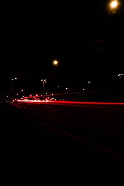 夜晚的车灯 夜路城漫漫长夜摄影路 道路上五彩斑斓的红光小径 背景墙纸的焦距模糊的照片 垂直复制空间 — 图库照片