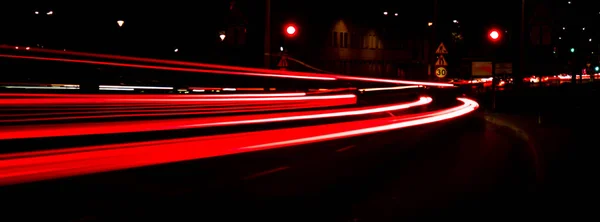 Lights of cars at night. Street line lights. Night highway city. Long exposure photograph night road. Colored bands of red light trails on the road. Background wallpaper defocused blurred photo. Banner size Copy space