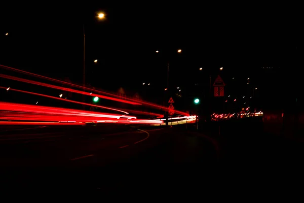 Lights of cars at night. Street line lights. Night highway city. Long exposure photograph night road. Colored bands of red light trails on the road. Background wallpaper defocused photo.