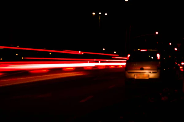 Lights of cars at night. Street line lights. Night highway city. Long exposure photograph night road. Colored bands of red light trails on the road. Background wallpaper defocused photo.