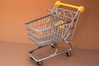Bej arka planda boş alışveriş arabası. Metnin için alanı kopyala. Çevrimiçi alışveriş, alışveriş merkezi market tüketicisi konsepti. Küçük oyuncak süpermarket market market arabası. Yemek krizi. Yükselen yiyecekler