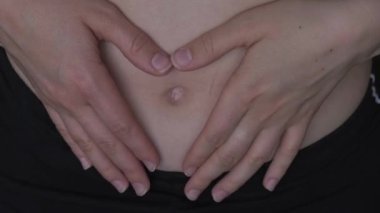 Formda ve zayıf göbekli kadının kalp sembolü. Fitness refah konsepti. Vücut bakımı, hamilelik, kilo verme diyeti konsepti. Bağırsak veya üreme sorunu olan bir kadın. Evde antrenman yapıyorum. Göbek bel.