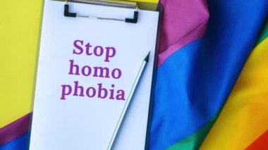 4k gökkuşağı bayrağını DUR HOMOPHOBIA mesaj kağıdıyla yakınlaştır. İpek kumaştan yapılmış gökkuşağı lgbtq bayrağı. LGBTQ gurur ayının sembolü. Eşit haklar. Barış ve özgürlük. LGBTQ Desteği