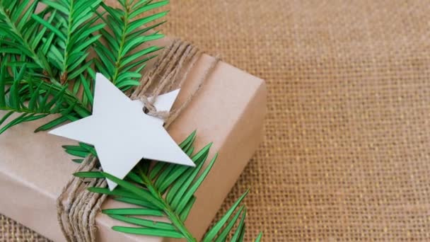 4Kは クラフト紙に包まれ モミの枝で飾られた 新年の贈り物と箱の中にズームアウトします 休日やギフトの概念 手作りエコフレンドリーな代替緑のクリスマスプレゼントゼロ廃棄物 — ストック動画