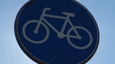 Round road sign depicting white bicycle on blue background, meaning mandatory bike path for cyclists against blue sky background. Blue round sign on bike path pole. Bike path
