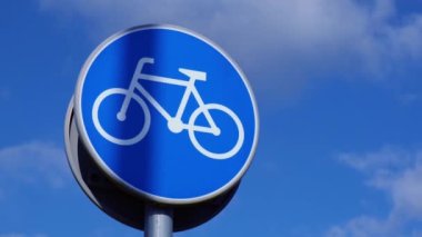 Round road sign depicting white bicycle on blue background, meaning mandatory bike path for cyclists against blue sky background. Blue round sign on bike path pole. Bike path