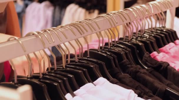 女人检查合适的尺寸和价格 女性手的特写拔出的气囊选择衣服 商场内妇女成衣分送手忙脚乱地穿过成排成排的购物服装 — 图库视频影像