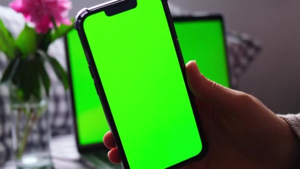 ノートパソコンのChromakeyでスマートフォンの緑の画面を使用して女性を閉じます 携帯電話を持っている女性の手のショットを閉じます 緑の画面の電話を使用してメモ帳に何かを書く女性 — ストック動画