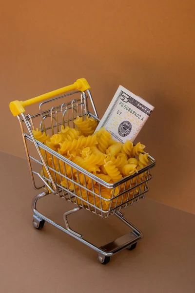 Καλάθι Άμαξας Αγορών Γεμάτο Ζυμαρικά Χαρτονόμισμα Δολαρίων Ηπα Φόντο Μπεζ — Φωτογραφία Αρχείου