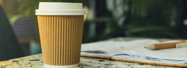 Kağıt not defteriyle kağıt bardakta sıcak latte kahve. Kafe masasında bir paket kağıt bardak. Verimli çalışma ve çalışma için kahveli Freelance Workspace defteri. Rahat çalışıyor.