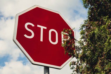 Red stop sign on metal pole on street. Road attention sign on cloudy background. Outdoors