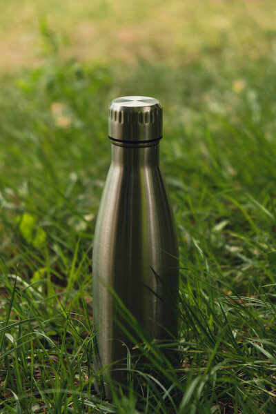 Бутылка воды. Многоразовая стальная термобутылка воды на зеленой траве. Устойчивый образ жизни. Пластиковая безотходная жизнь. Вперед, зеленая охрана окружающей среды. Забота о здоровье. Стальная термо вода