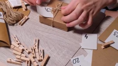 Tanınmayan genç bir kadın el işi çantasına numara yapıştırıyor, mandalla tutturuyor. Ev yapımı takvim için el yapımı kraft kâğıdı yapan bir kadın. Kendi ellerinle adım adım kendin yap.