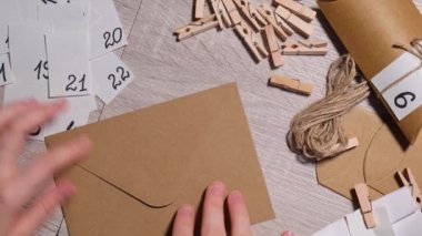 Tanınmayan genç bir kadın el işi çantasına numara yapıştırıyor, mandalla tutturuyor. Ev yapımı takvim için el yapımı kraft kâğıdı yapan bir kadın. Kendi ellerinle adım adım kendin yap.