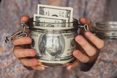 Dollar banknote saving money in glass jar. Unrecognizable woman moderate consumption and economy Collecting money. Tips. Business, finance, saving, banking and people concept. Extra money, passive