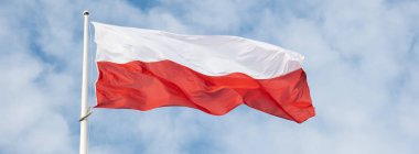 Güzel mavi gökyüzüne doğru dalgalanan Polonya bayrağı. Polonya bayrağı mavi gökyüzünde beyaz ve kırmızı dalgalanıyor. Polonya 'nın ulusal bayrağı bayrak direğinde dalgalanıyor.