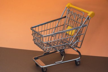 Bej arka planda boş alışveriş arabası. Metnin için alanı kopyala. Çevrimiçi alışveriş, alışveriş merkezi market tüketicisi konsepti. Küçük oyuncak süpermarket market market arabası. Yemek krizi. Yükselen yiyecekler