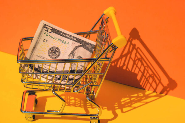 Корзина тележки на ярко-оранжевом желтом фоне. Скопируйте место для текста. Интернет-шопинг, покупка потребительской концепции mall market shop. Маленькая игрушка
