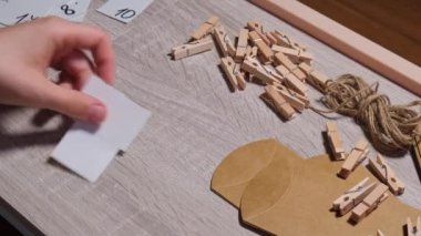 Tanınmayan genç bir kadın el işi çantasına numara yapıştırıyor, mandalla tutturuyor. Ev yapımı takvim için el yapımı kraft kâğıdı yapan bir kadın. Kendi ellerinle adım adım kendin yap.