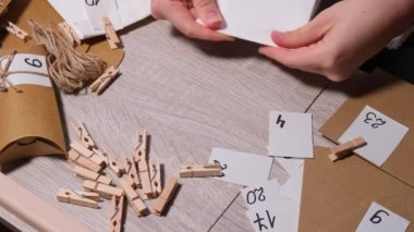 Tanınmayan genç bir kadın el işi çantasına numara yapıştırıyor, mandalla tutturuyor. Ev yapımı takvim için el yapımı kraft kâğıdı yapan bir kadın. Kendi ellerinle adım adım kendin yap.