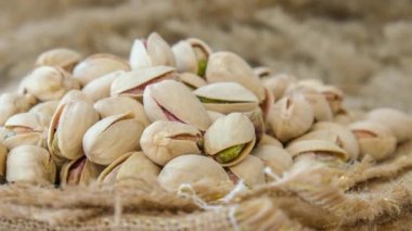 4k zoom in out Pistachios in burlap sack on concrete table. Organic pistachios. Vegan Healthy food high protein. Dietary nutrition. Concept of nuts omega vitamin