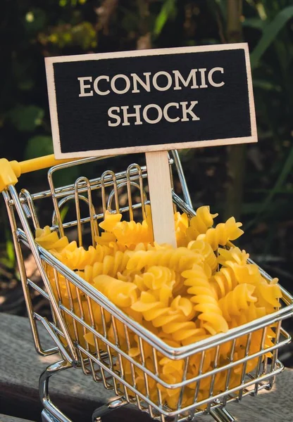 Economic Shock Tekst Etykiecie Tablicy Przed Wózkiem Zakupy Wypełnione Makaronem — Zdjęcie stockowe