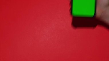 Kırmızı arka planda krom ekranlı Noel Baba-Beyaz şapkalı cep telefonu. Noel ya da yeni yıl tatili kavramı. Kadın El 'in elinde boş cep telefonu var. Dijital aygıt