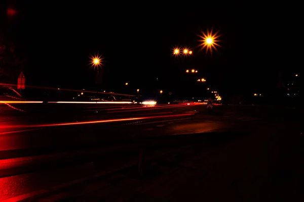 Lights of cars at night. Street line lights. Night highway city. Long exposure photograph night road. Colored bands of red light trails on the road. Background wallpaper defocused blurred photo