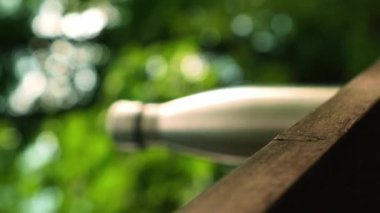 Su şişesi. Ahşap bank izometrik konseptinde yeniden kullanılabilir çelik termo su şişesi. Sürdürülebilir yaşam tarzı. Plastiksiz sıfır atıksız yaşam. Yeşil çevre korumasına geçin. Sağlık bilinci yerinde. Çelik