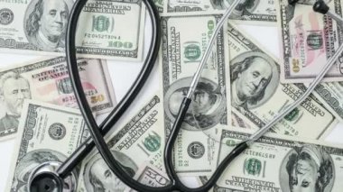4 bin dolar ve stetoskop yığınını yakınlaştır. Tıbbi pahalı ilaç konsepti, doktor maaşı. Uzayı metin için kopyala. Sağlık sigortası. Aşı masrafları. Finansal kriz. Kapalı