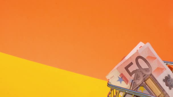 手推玩具超市推车50欧元钞票钱在购物车黄色背景 销售一篮子欧元钞票 最低工资概念 投资养恤金 储蓄资金 — 图库视频影像