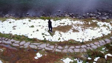 Polonya Tatry dağlarındaki Morskie Oko Karlı Dağ Kulübesi yakınlarında Rysamy veya Black Pond gölünün keyfini çıkaran mutlu kadın, insansız hava aracı manzarası, Zakopane, Polonya. Doğayla bütünlük. Havadan görüntüler.